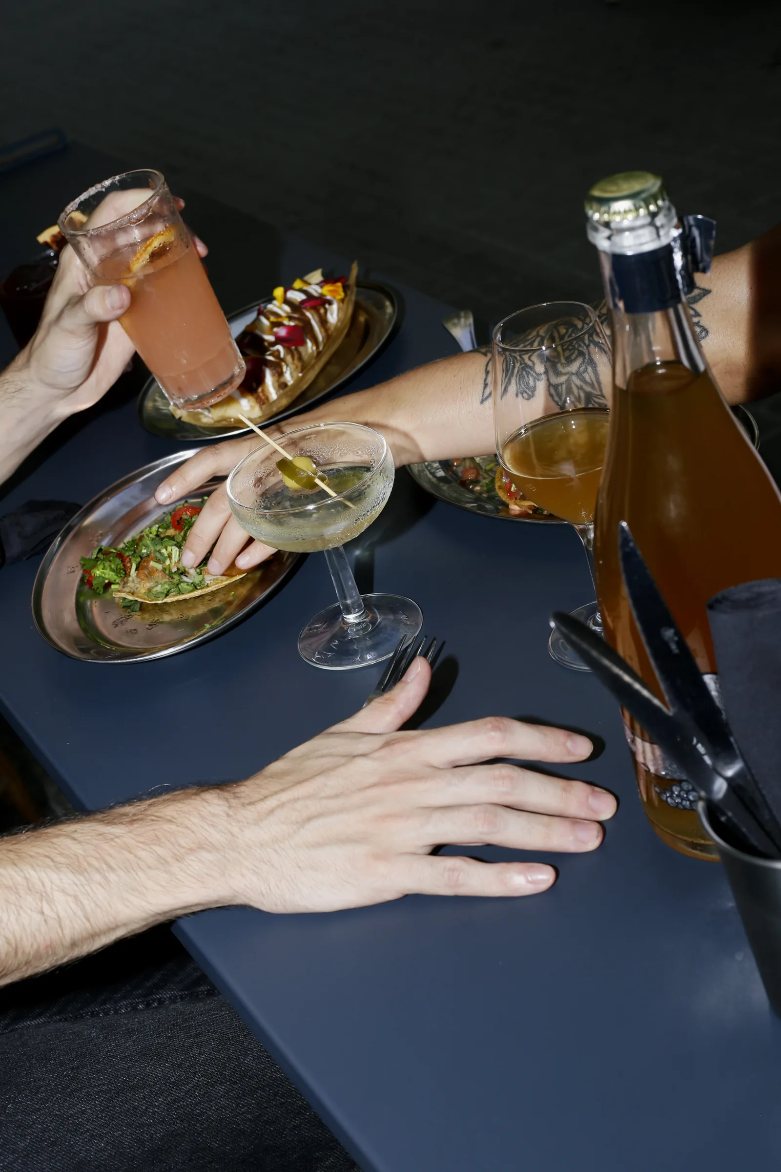 Mesa con manos, copas y una botella