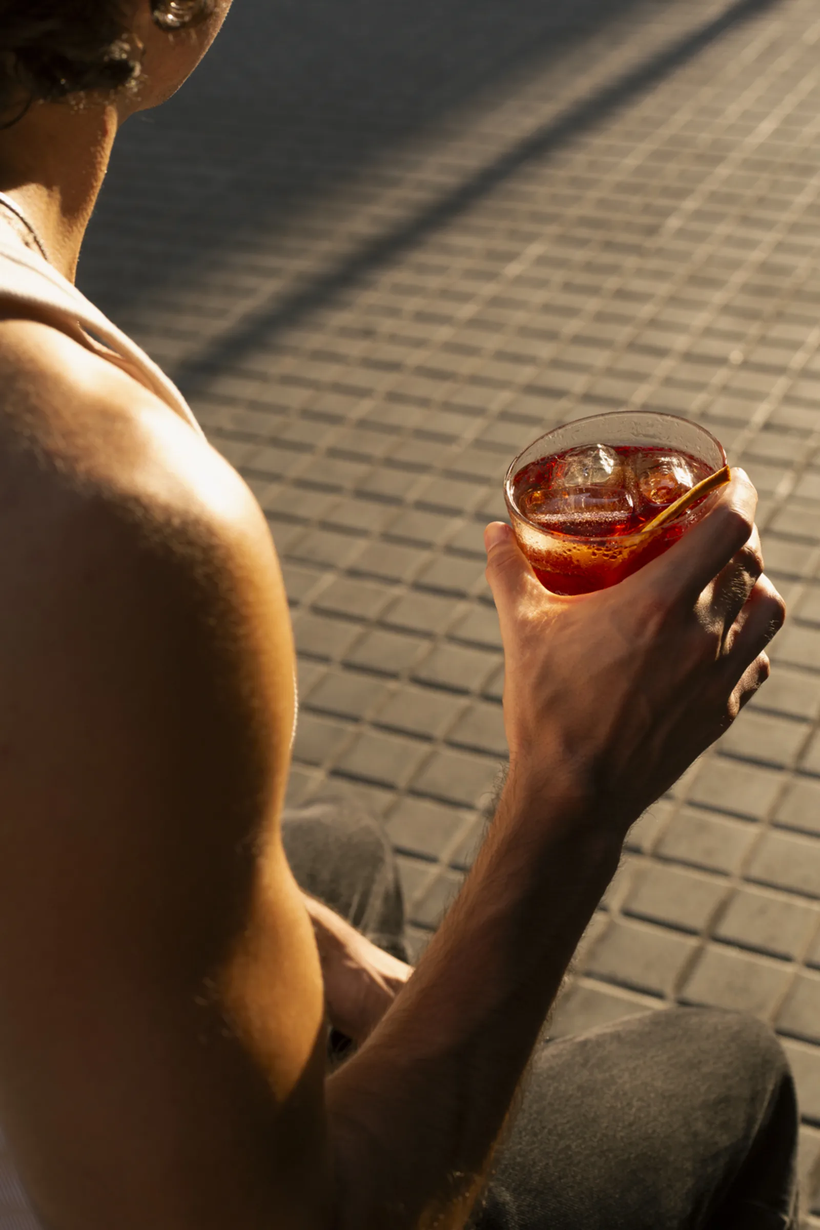 Brazo al sol en la calle con una copa en la mano