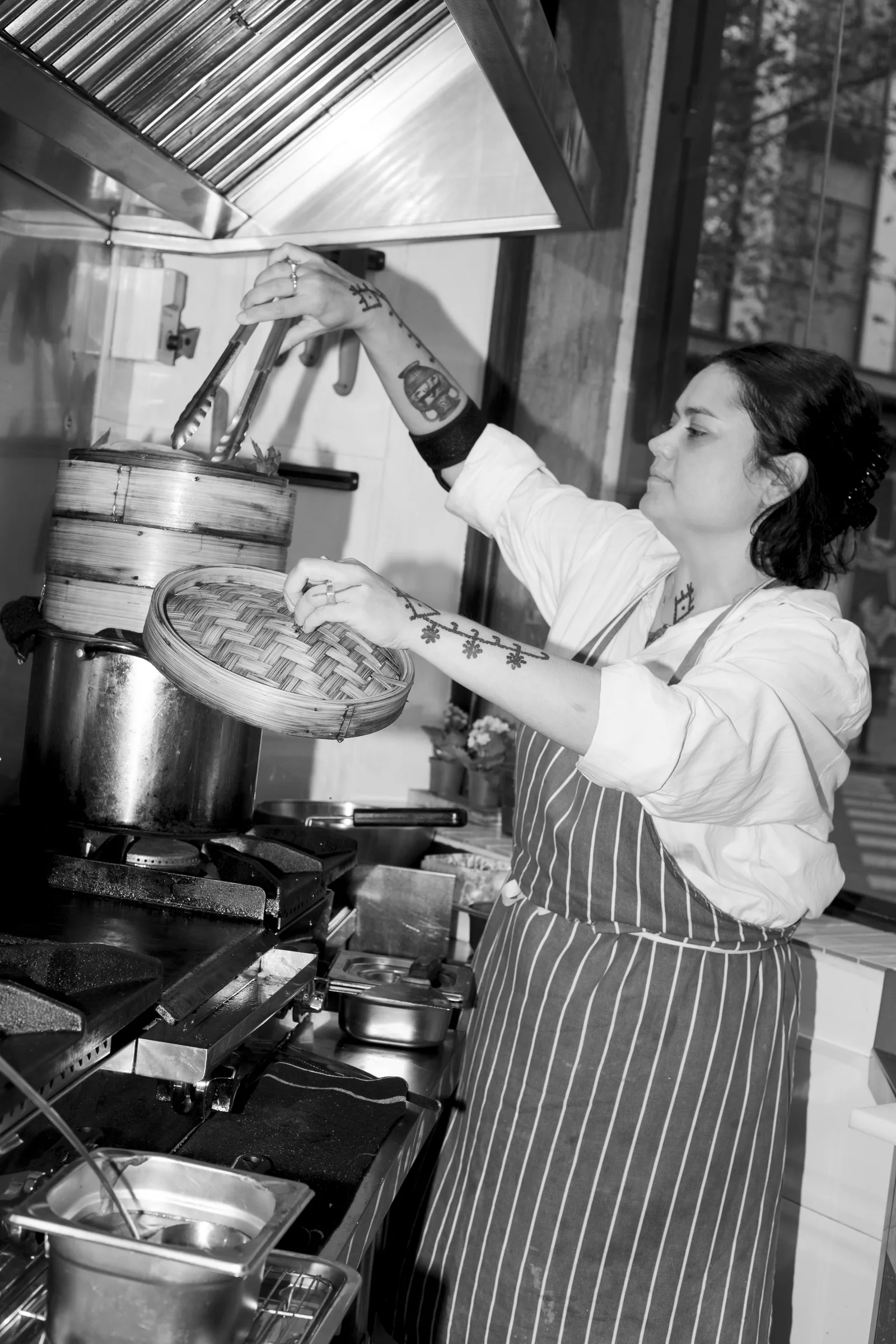 Cocinera trabajando junto a los fogones, en blanco y negro