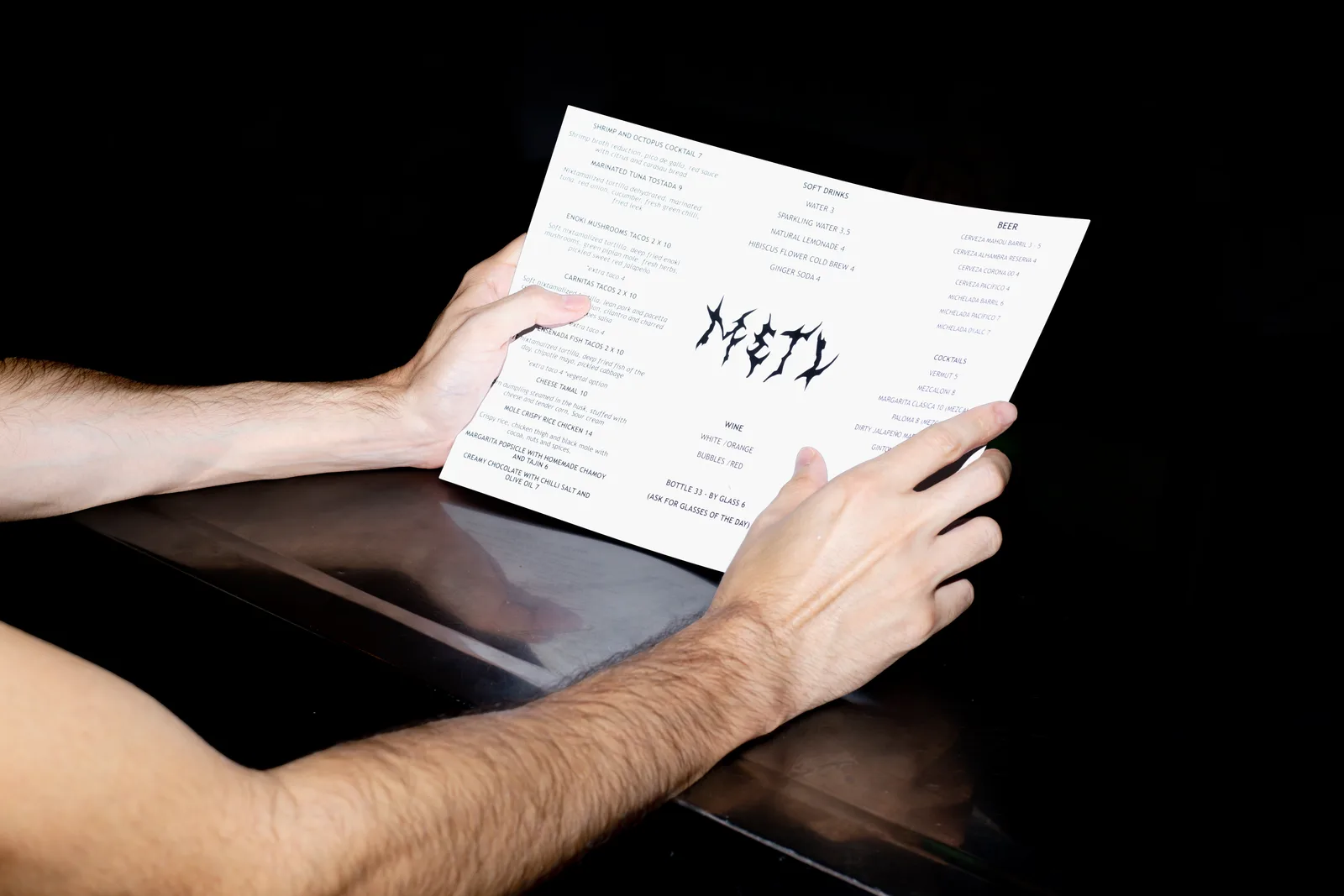 Manos sosteniendo la carta de METL