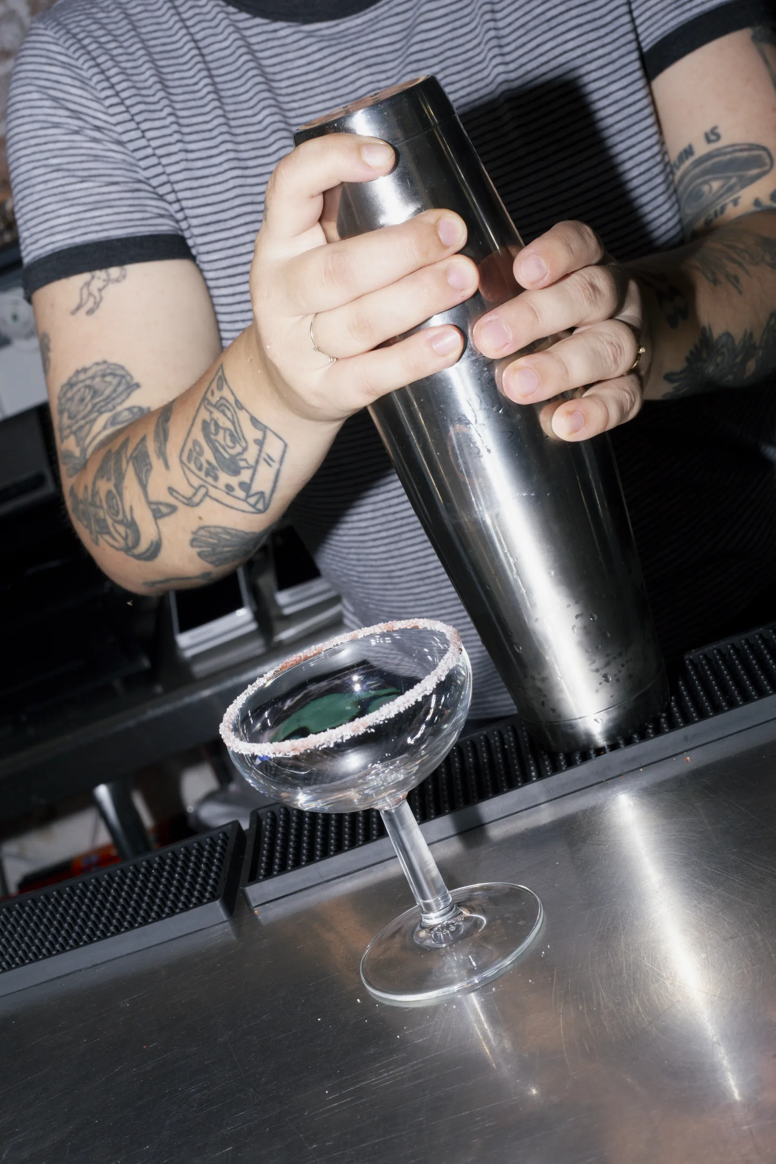 Barman agitando la coctelera tras la barra