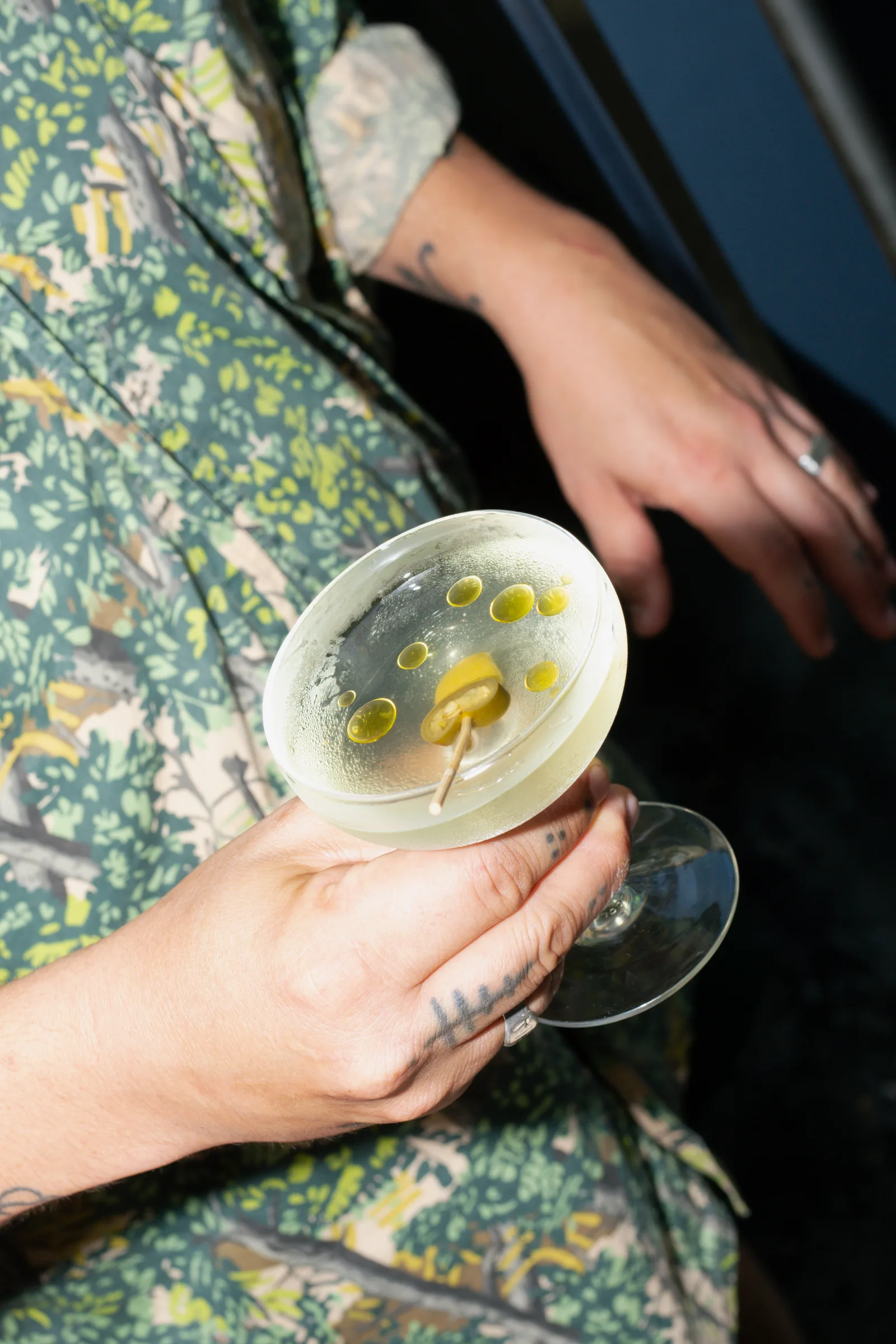 Mano con camisa floral sosteniendo un martini