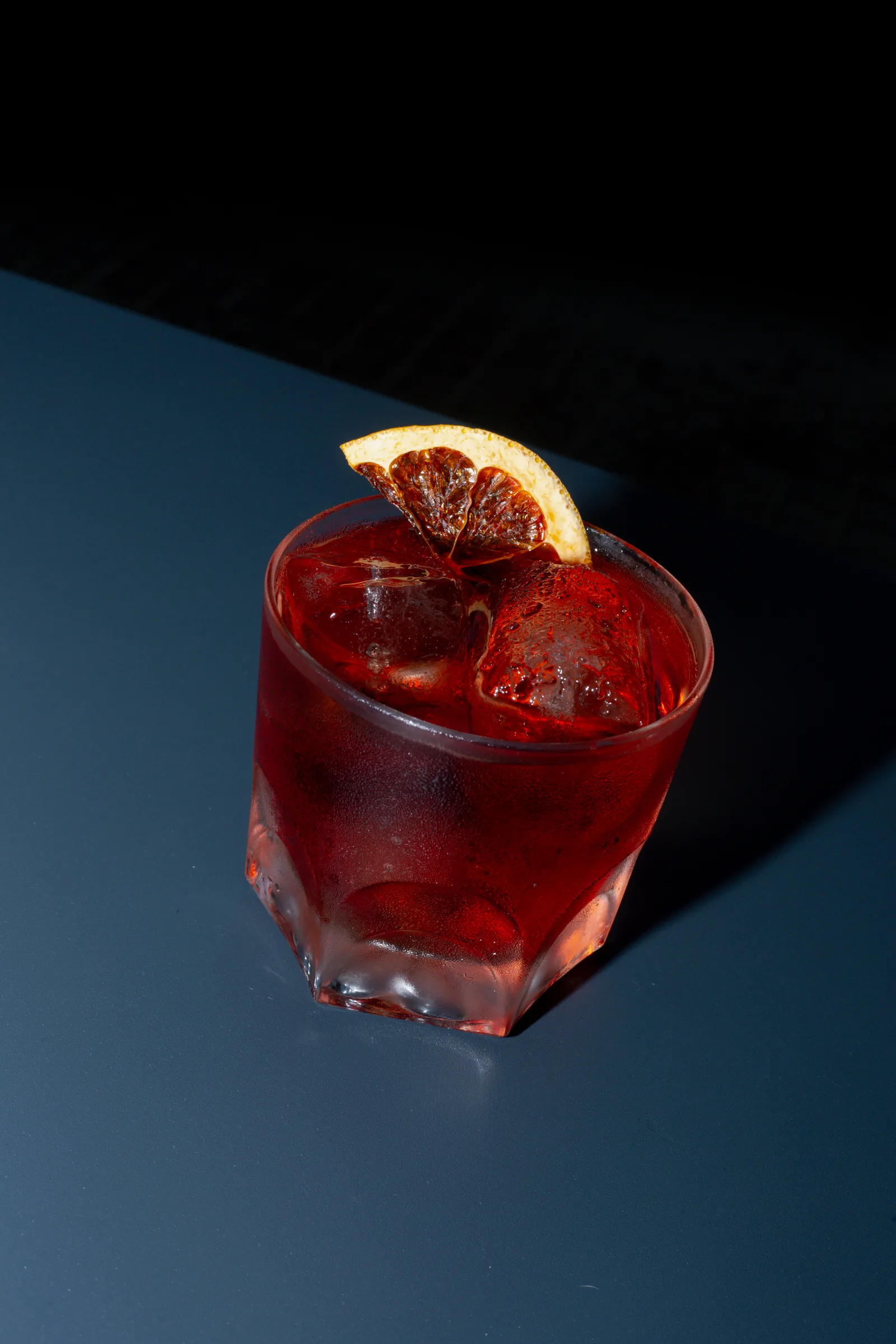 Negroni rojo sobre mesa azul marino